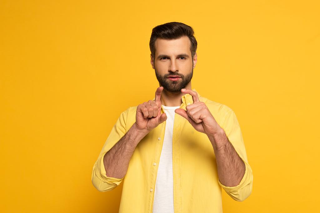 Бородатий чоловік показує жест глухою і ніжною мовою на жовтому тлі
 - Фото, зображення