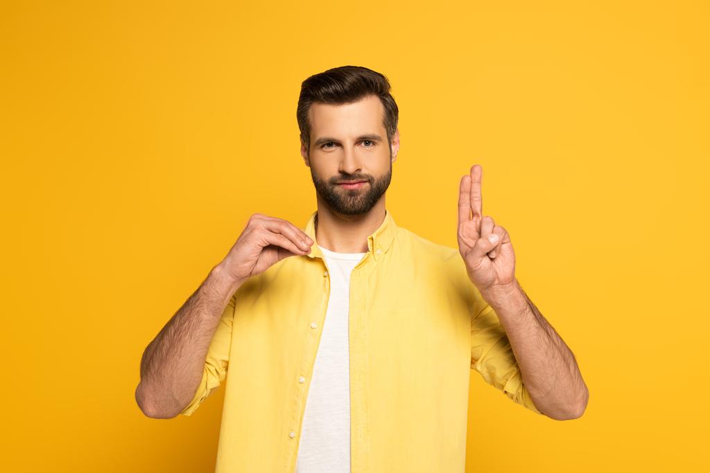Bearded man showing letters while using deaf and dumb language on yellow background - 写真・画像