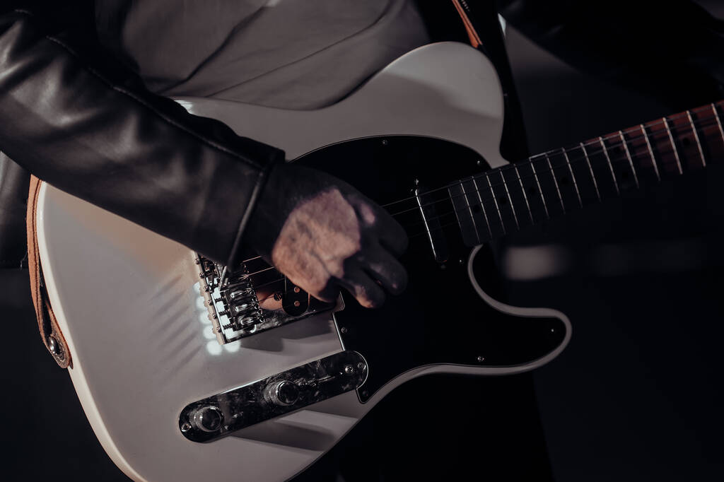 Γκρο πλαν άποψη του ροκ μουσικός mans χέρια αριστοτεχνικά παίζει ηλεκτρική κιθάρα. Δάχτυλα που χτυπούν χορδές στο καπνιστό προσκήνιο κατά τη διάρκεια της συναυλίας στη σκηνή. - Φωτογραφία, εικόνα