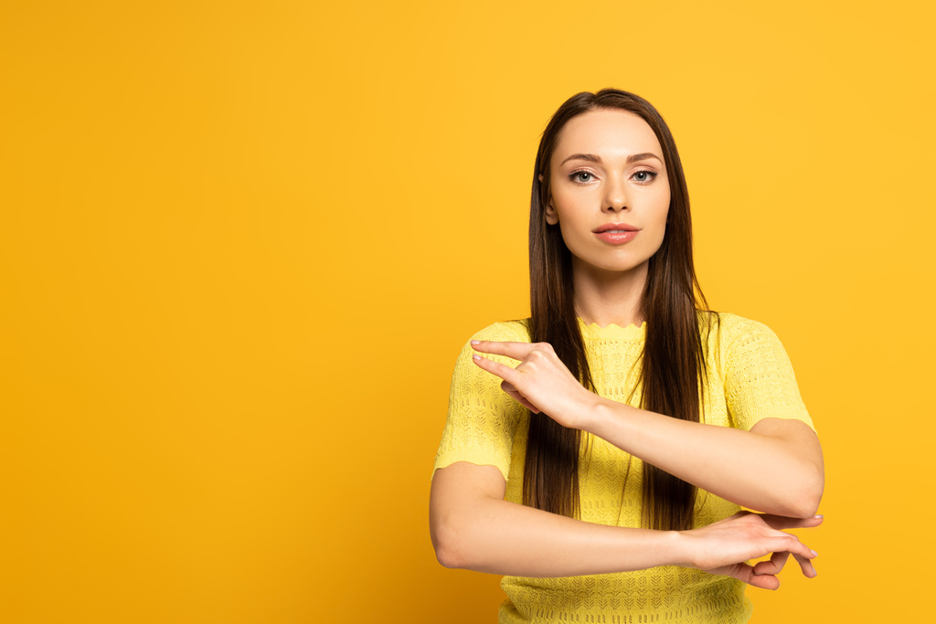 Beautiful woman showing word from deaf and dumb language on yellow background - Photo, Image