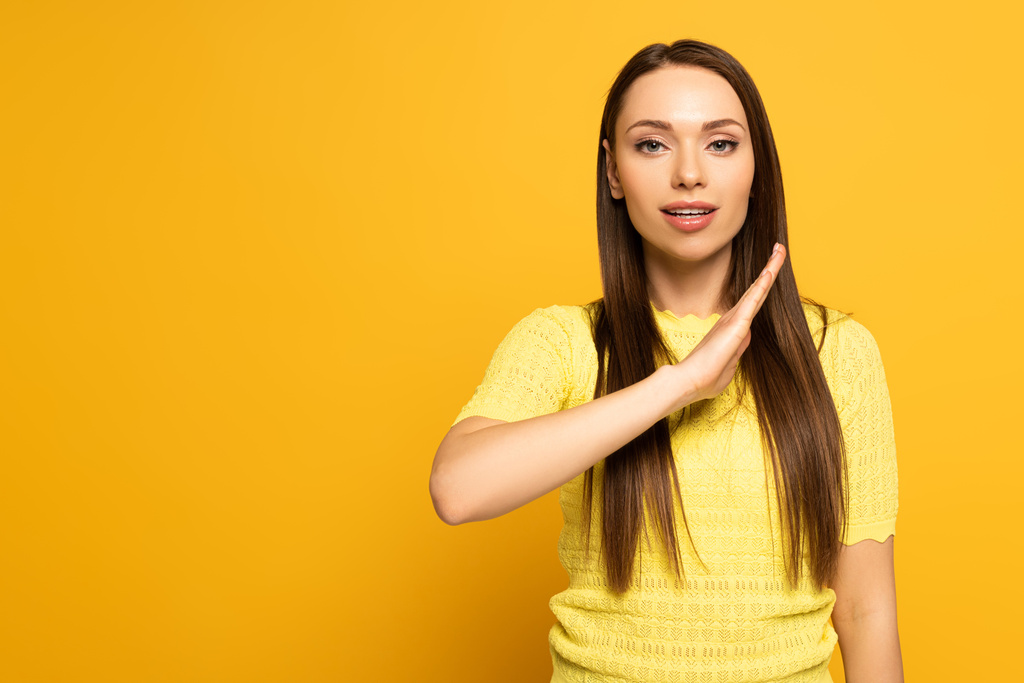 Beautiful girl using deaf and dumb language on yellow background - 写真・画像