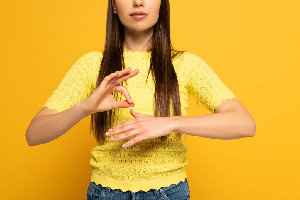Обрізаний вид жінки з використанням мови жестів на жовтому тлі
 - Фото, зображення