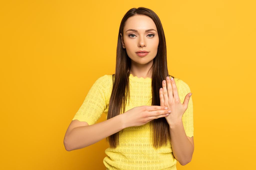 Привлекательная девушка с языком жестов на желтом фоне
 - Фото, изображение