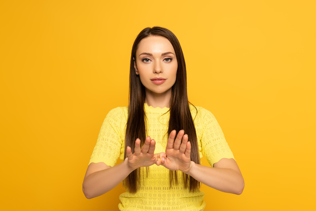 Belle femme montrant signe dans un langage sourd et muet sur fond jaune
 - Photo, image