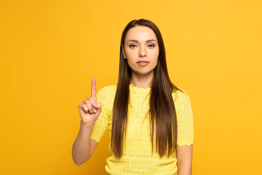 Ελκυστική κοπέλα δείχνει με το δάχτυλο σε κίτρινο φόντο - Φωτογραφία, εικόνα