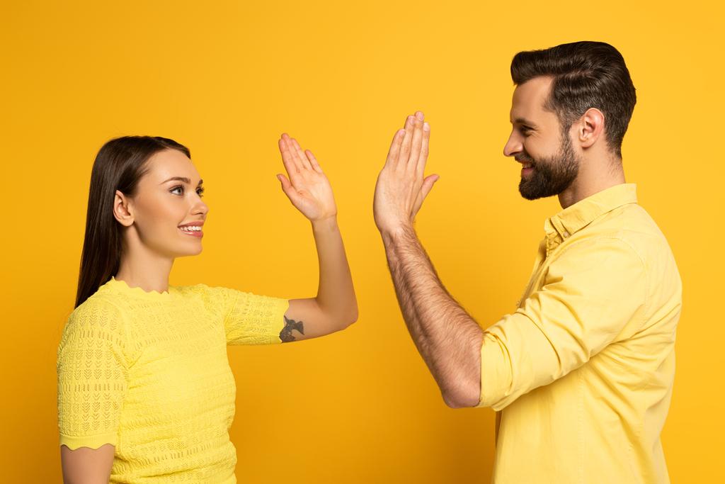 Young smiling couple high five on yellow background - Photo, Image