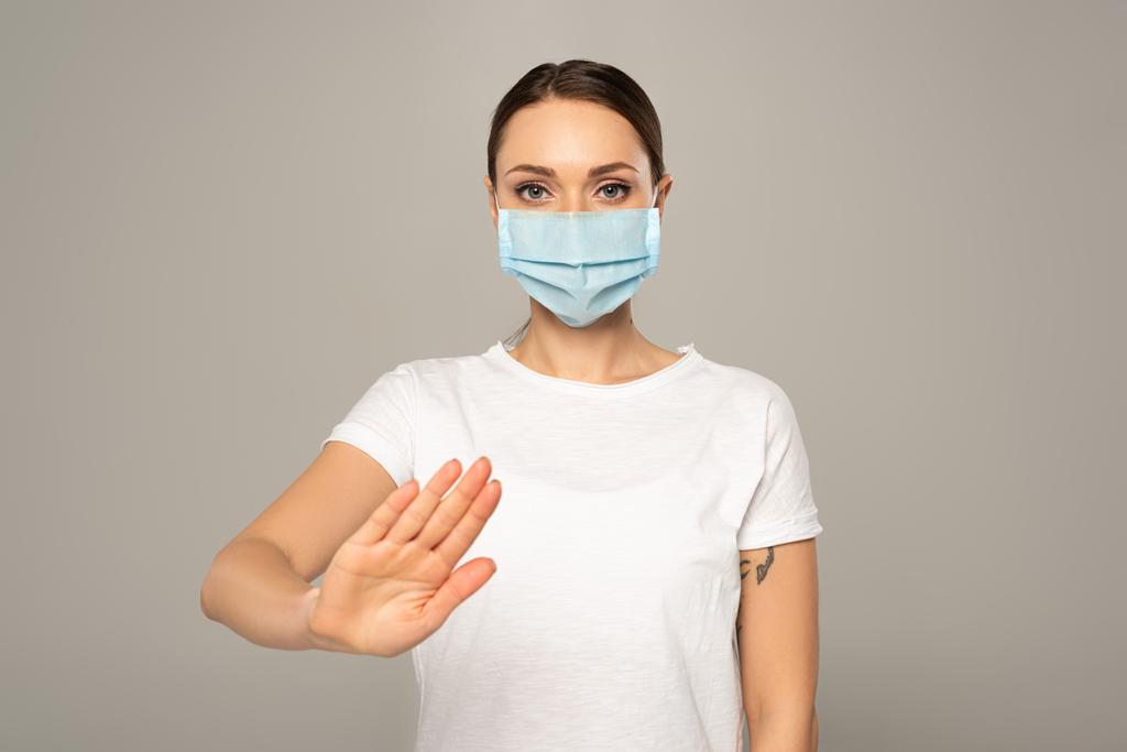 Donna in maschera medica mostrando stop gesto isolato su grigio
  - Foto, immagini