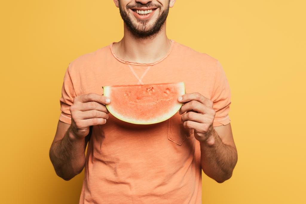abgeschnittene Ansicht eines lächelnden Mannes mit einer Scheibe reifer, saftiger Ananas auf gelbem Hintergrund - Foto, Bild