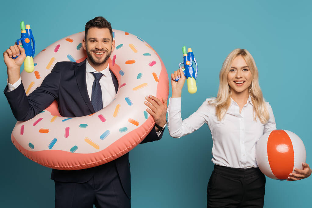 šťastní podnikatelé s plaveckým kroužkem a nafukovací míč drží vodní zbraně na modrém pozadí - Fotografie, Obrázek