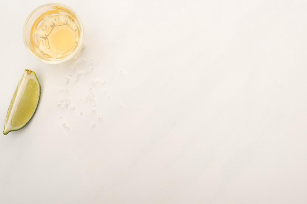 vista superior da tequila dourada com limão na superfície de mármore branco
 - Foto, Imagem