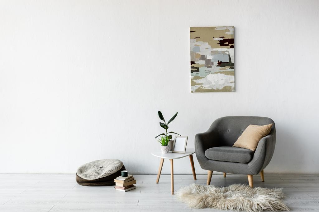 モダンなリビングルームの緑の植物、フレームと壁に絵とコーヒーテーブルの近くの快適なアームチェア  - 写真・画像