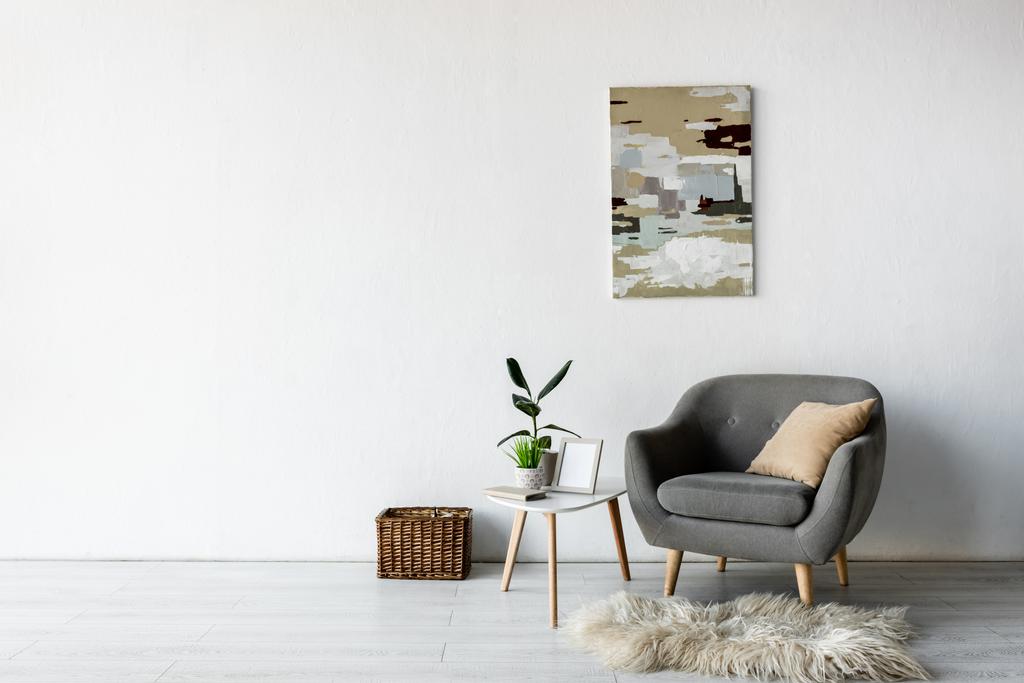 poltrona cinza confortável perto da mesa de café com plantas verdes e moldura na sala de estar moderna
  - Foto, Imagem
