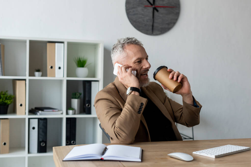 hombre de negocios guapo hablando en el teléfono inteligente y la celebración de café para ir en la oficina
  - Foto, imagen