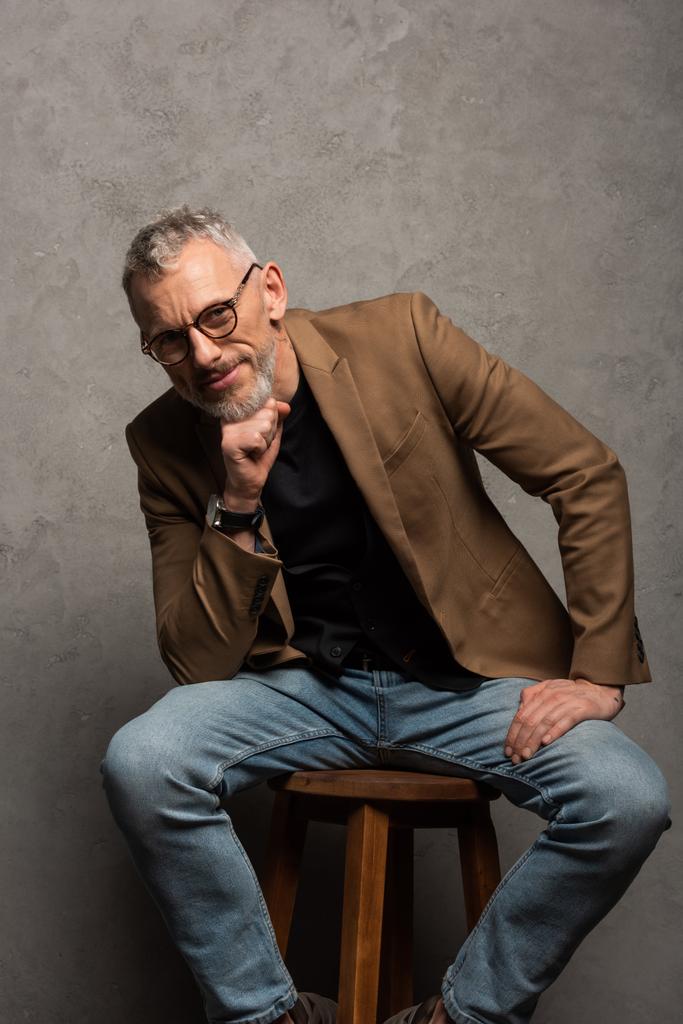 homem de negócios feliz em óculos olhando para a câmera enquanto sentado em cinza
  - Foto, Imagem