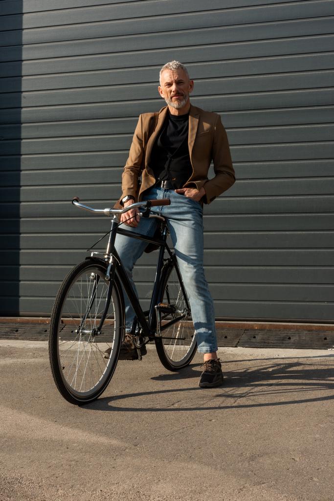 φως του ήλιου σε όμορφος επιχειρηματίας με το χέρι στην τσέπη κοντά στο ποδήλατο έξω  - Φωτογραφία, εικόνα