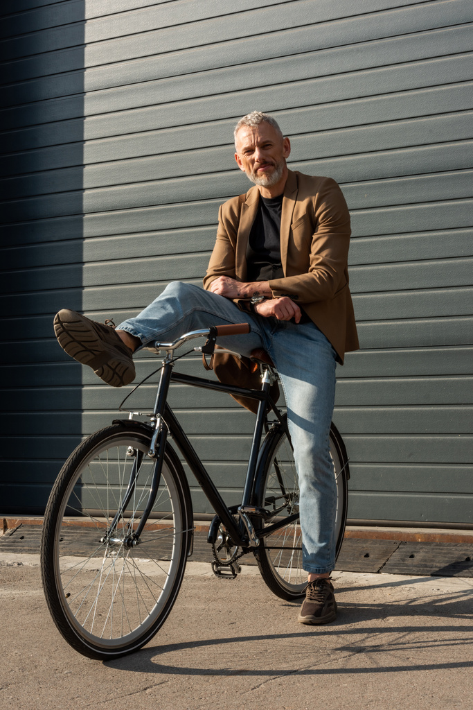 luz del sol en hombre de negocios guapo posando cerca de la bicicleta fuera
  - Foto, Imagen