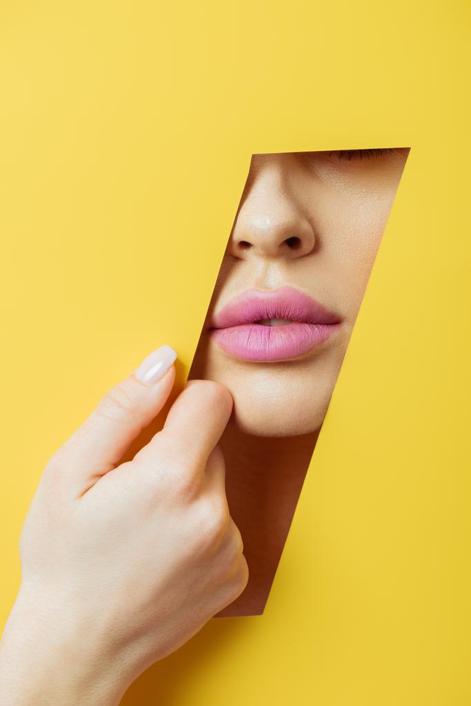 Vista parcial de mujer con labios rosados tocando papel amarillo
  - Foto, imagen