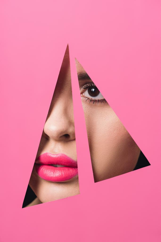 Γυναικείο πρόσωπο με ροζ χείλη σε τριγωνικές τρύπες σε χαρτί - Φωτογραφία, εικόνα