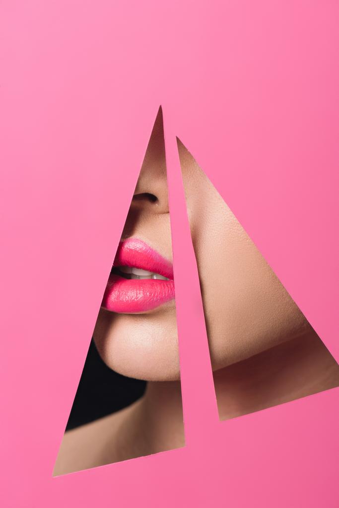 Vista ritagliata del viso femminile con labbra rosa in fori triangolari in carta su nero
 - Foto, immagini