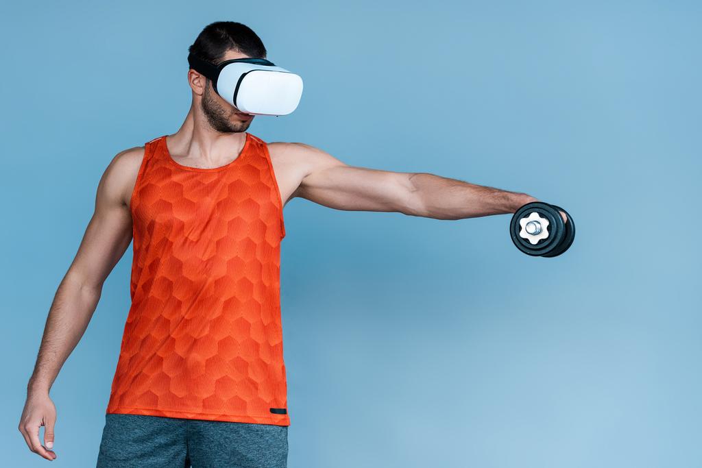 man in virtual reality headset uit te werken met halter op blauw - Foto, afbeelding