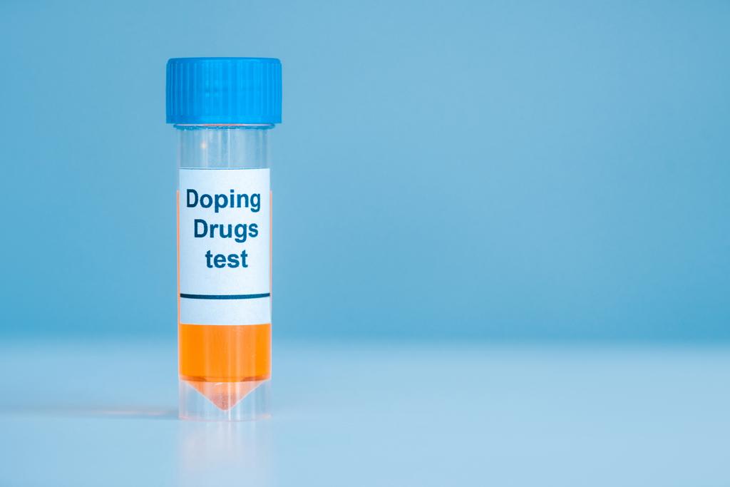 container met urinemonster en doping drugs test belettering op blauw  - Foto, afbeelding