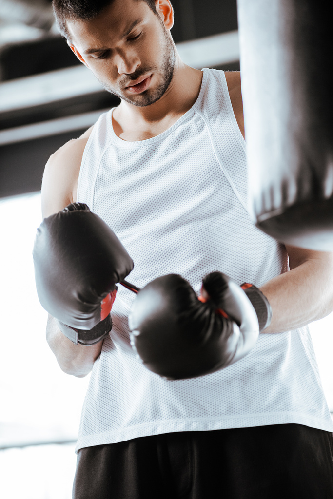 selektywne skupienie się sportowca patrząc na czarne rękawice bokserskie w centrum sportowym  - Zdjęcie, obraz