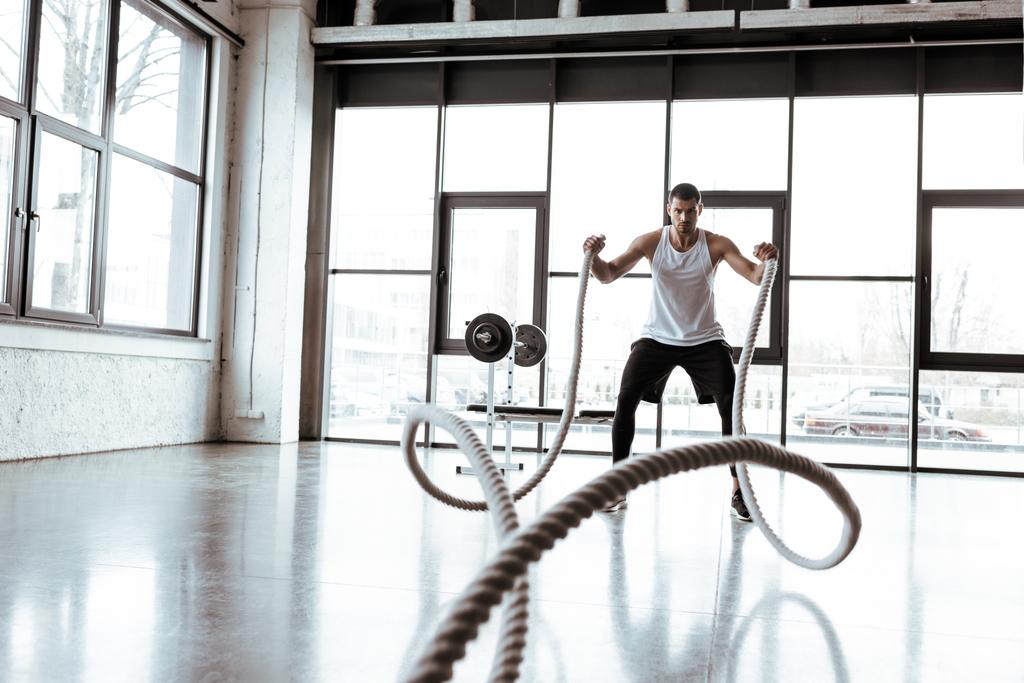 foco seletivo do desportista exercitando com cordas de batalha no ginásio moderno
  - Foto, Imagem