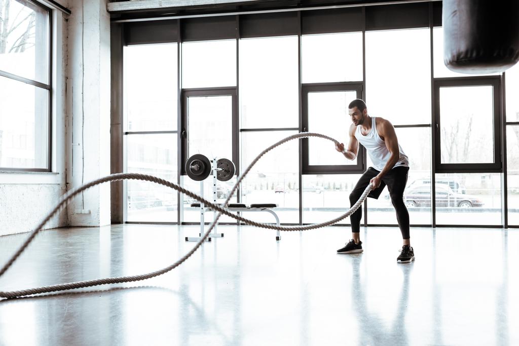 επιλεκτική εστίαση του ισχυρού αθλητή άσκηση με σχοινιά μάχης στο σύγχρονο γυμναστήριο  - Φωτογραφία, εικόνα