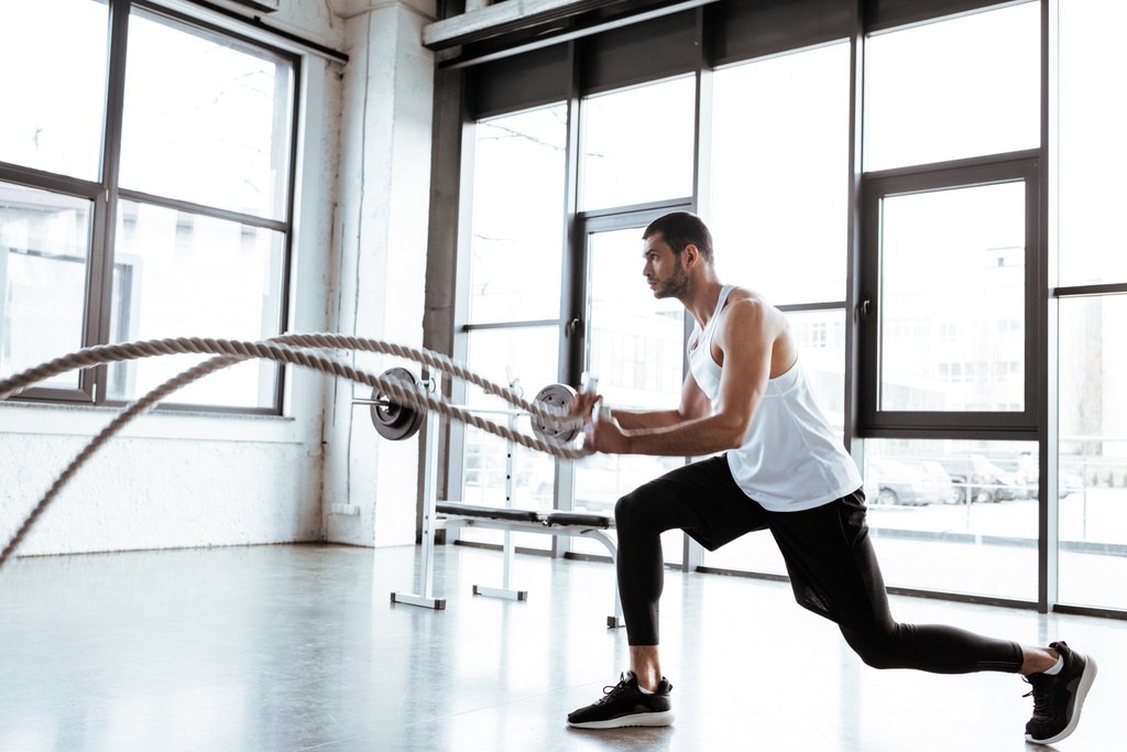 desportista barbudo exercitando com cordas de batalha no ginásio moderno
  - Foto, Imagem