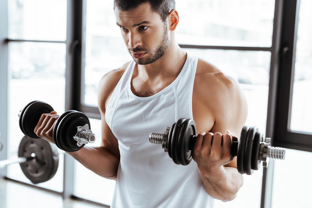 bearded sportsman exercising with dumbbells in gym  - Photo, Image