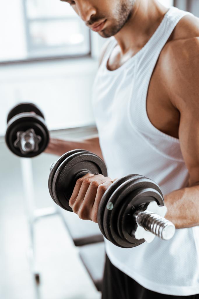 vista recortada de deportista atlético haciendo ejercicio con pesas en el gimnasio
   - Foto, imagen