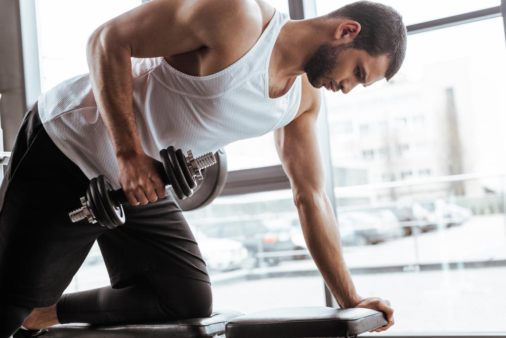hombre atlético haciendo ejercicio con mancuerna en el gimnasio
   - Foto, imagen