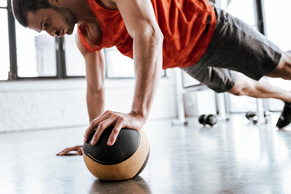 enfoque selectivo de deportista guapo haciendo ejercicio de tablón con pelota
  - Foto, imagen