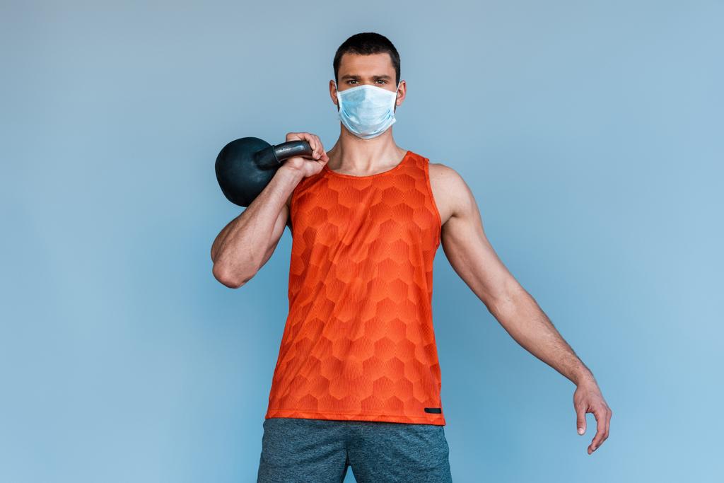 sportovec v lékařské masce cvičení s činka izolované na modré  - Fotografie, Obrázek
