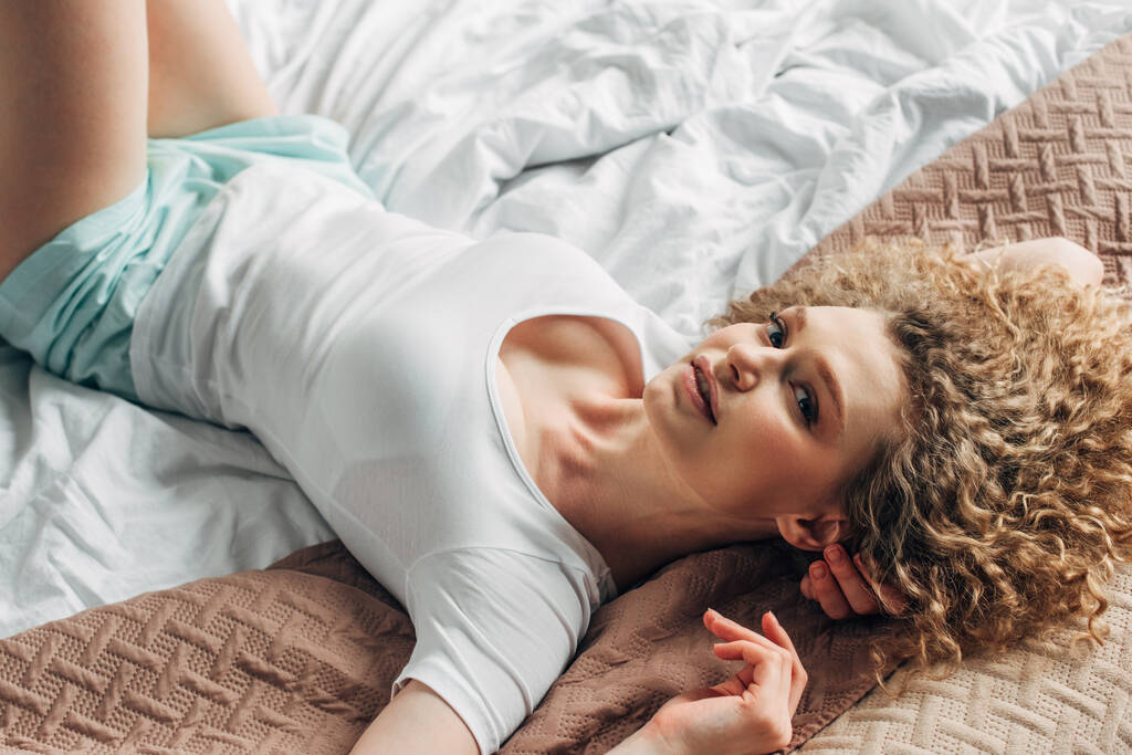 aantrekkelijk meisje in huiskleding liggend op bed in de ochtend   - Foto, afbeelding