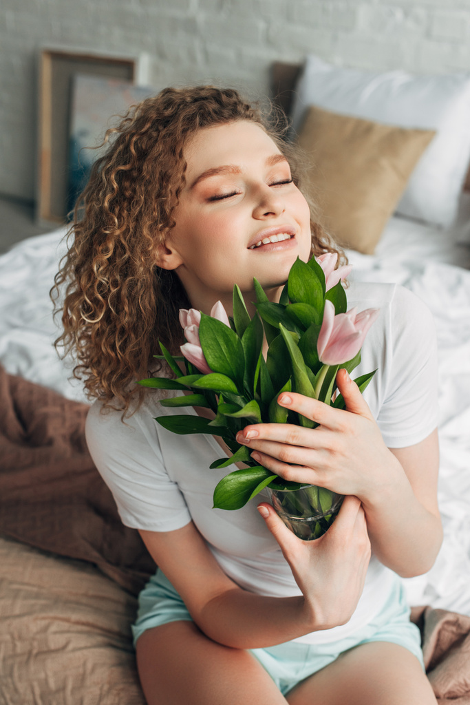 boldog vonzó lány otthoni viselet kezében tulipán virágok reggel   - Fotó, kép