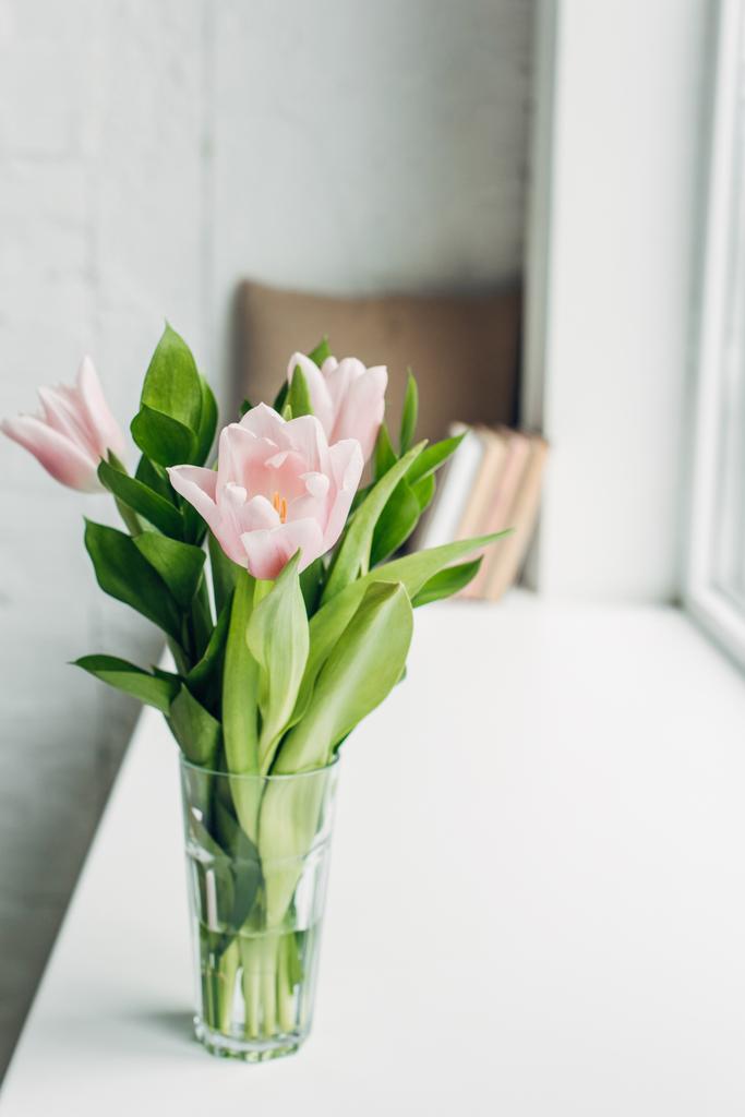 букет розовых цветов тюльпана в стакане на подоконнике с книгами
 - Фото, изображение
