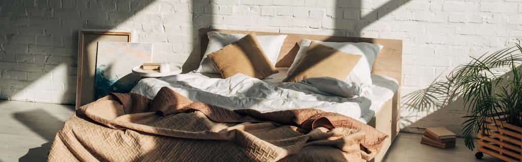 wnętrze sypialni z łóżkiem, poduszki i obrazy w świetle słonecznym z cieniami, orientacja panoramiczna - Zdjęcie, obraz