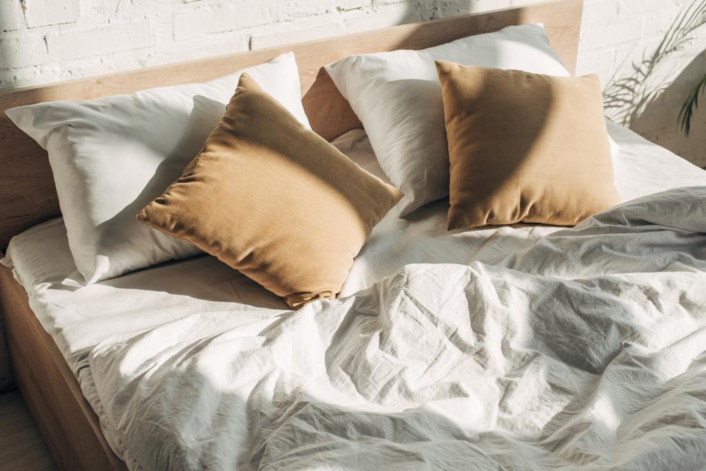 κρεβάτι με μαξιλάρια με ήλιο και σκιές - Φωτογραφία, εικόνα