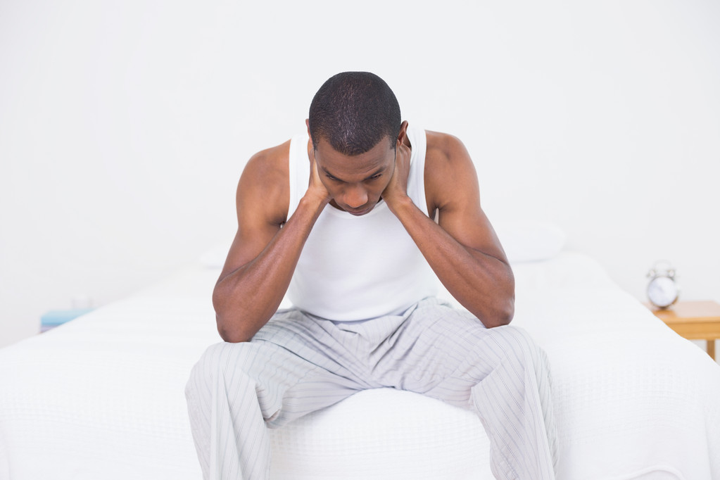 Задумчивый афро-человек сидит на кровати
 - Фото, изображение