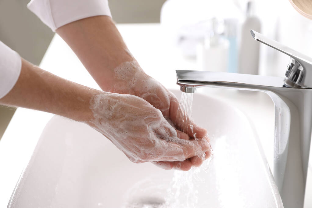 Чоловік, який миє руки з милом над раковиною у ванній кімнаті. - Фото, зображення