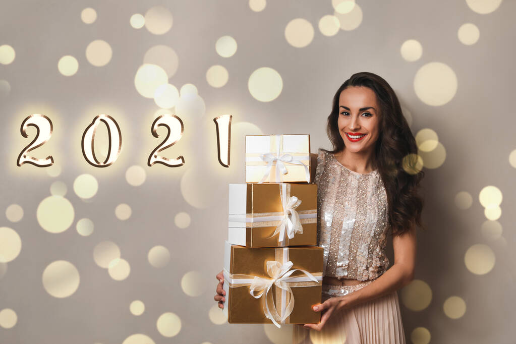Hermosa mujer con cajas de regalo sobre fondo beige. Celebración de Navidad
 - Foto, imagen