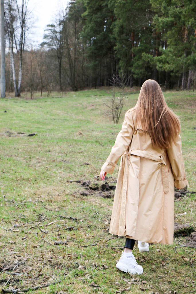 belle fille, blonde aux cheveux longs, se promène au printemps près de la forêt en manteau marron., sérénité et liberté
 - Photo, image