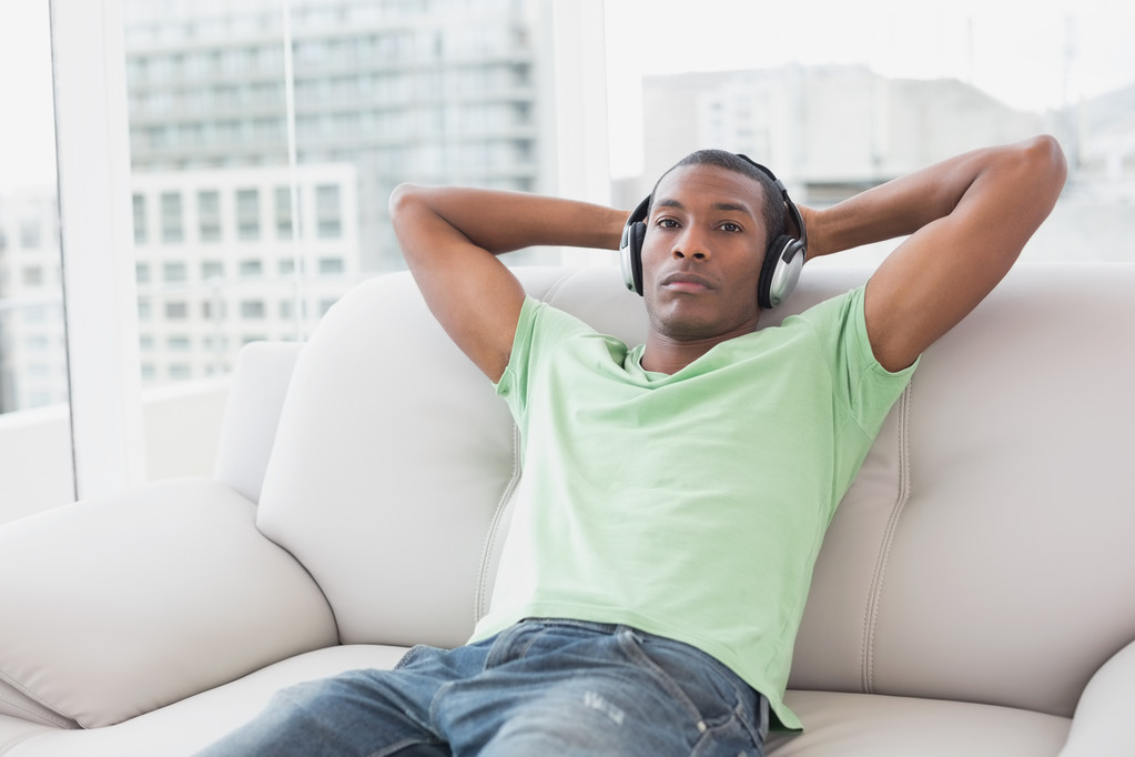 χαλαρή Αφρο άνθρωπος με ακουστικά που κάθεται στον καναπέ στο σπίτι - Φωτογραφία, εικόνα