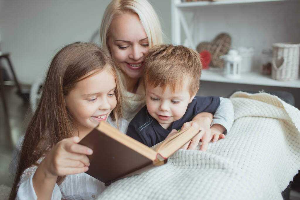 La famiglia nel periodo di auto-isolamento legge libri a casa sul divano. Come tenersi occupati durante la quarantena senza uscire di casa
 - Foto, immagini