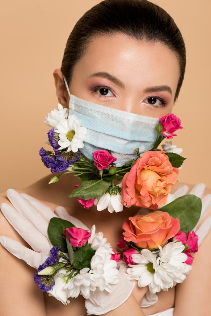 aantrekkelijk naakt aziatisch meisje in latex handschoenen en bloemen gezicht masker geïsoleerd op beige - Foto, afbeelding