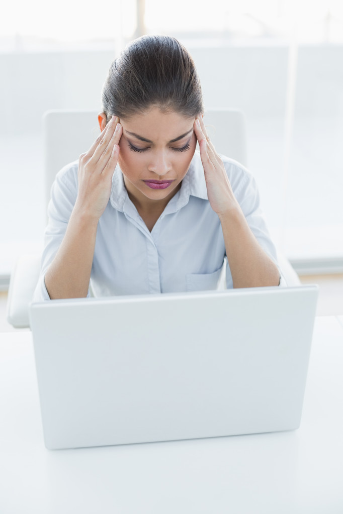 Бизнесвумен, страдающая головной болью с ноутбуком в офисе
 - Фото, изображение