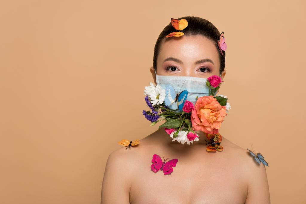 beautiful asian woman in floral face mask with butterflies isolated on beige - Photo, Image