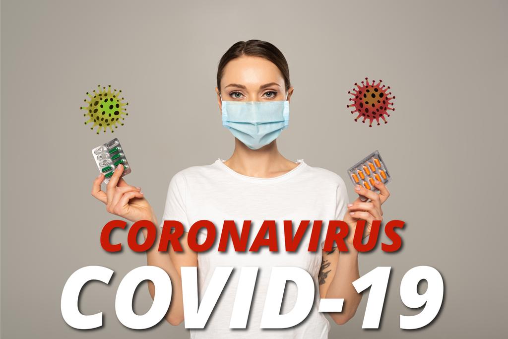 Žena v masce drží puchýře s pilulkami izolovanými na šedé, coronavirus covid-19 a bakterie ilustrace - Fotografie, Obrázek