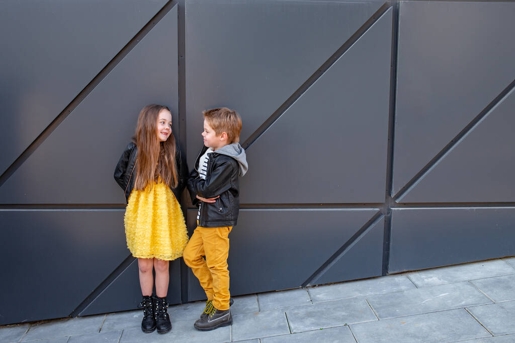 A kisgyerekek együtt járnak. Stílusosan öltözött, divatos gyerekek. Egy tinédzser sárga farmerban, és egy lány sárga ruhában.. - Fotó, kép